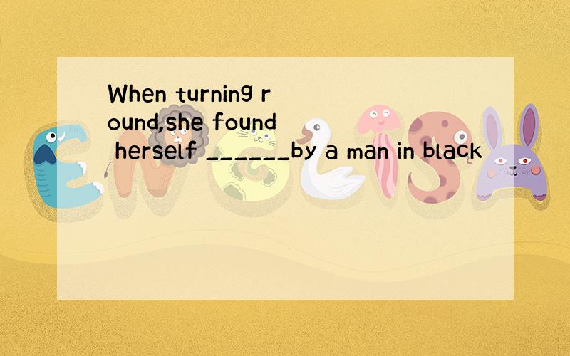 When turning round,she found herself ______by a man in black